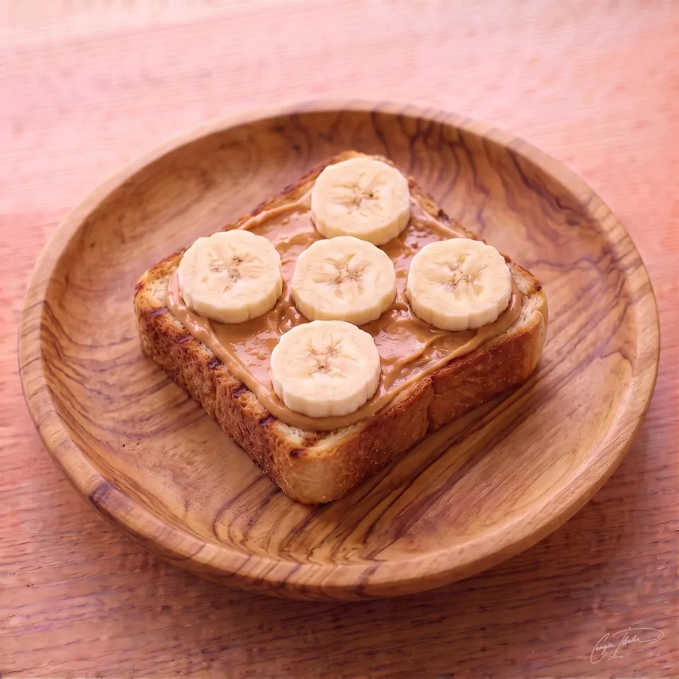 A thick, toasted square slice of bread resting on a carved wooden plate, generously spread with smooth peanut butter and topped with five perfectly arranged banana slices.