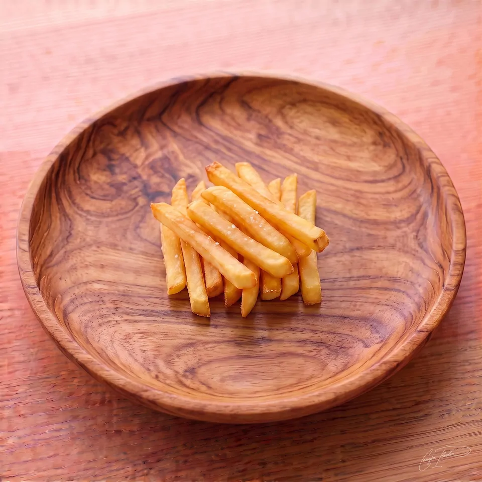 A neatly stacked pile of golden, perfectly fried patates kızartması (French fries) lightly dusted with coarse salt, served in a carved wooden bowl.